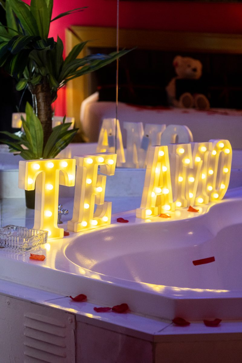Letras luminosas TE AMO sobre tina con pétalos de rosa